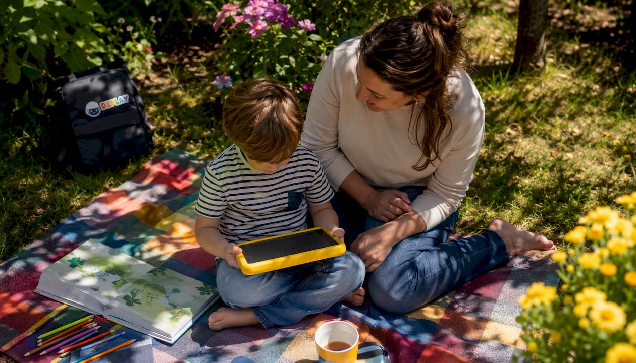 Een moeder en haar kind zitten samen aan tafel en ontdekken spelenderwijs nieuwe kindertechnologie.